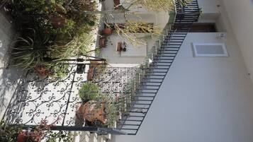 Ein Innenhof mit Treppe, Blumentöpfen und einem weißen Gebäude.