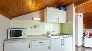 A kitchen with white cabinets, a microwave, a sink, and a stove. - Breathtaking View - Attic Apartment (Dubrovnik)