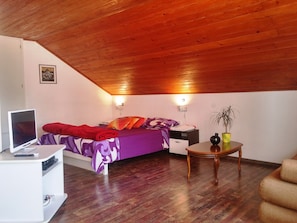 A bedroom with a bed, bedside tables, a desk with a computer, and a small table with a plant. - Breathtaking View - Attic Apartment (Dubrovnik)