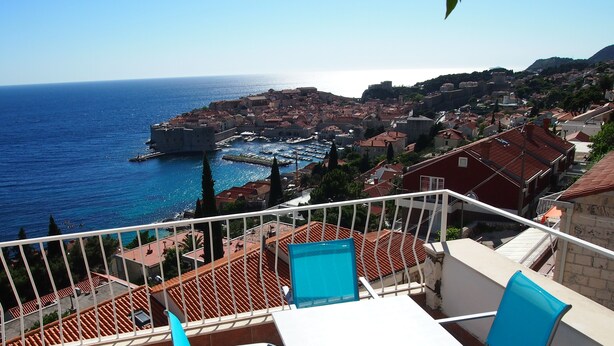 A terrace with a table and chairs overlooking a coastal town with historic buildings and a harbor. - Breathtaking View - Attic Apartment (Dubrovnik)