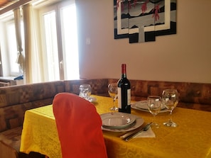A dining area with a table set for two, a bottle of wine, and a painting on the wall. - Breathtaking View - Attic Apartment (Dubrovnik)