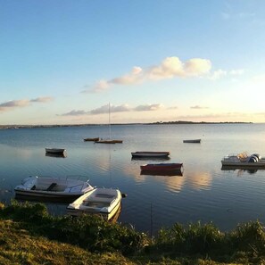 A calm lake with several boats anchored, surrounded by grassy areas and a distant shoreline. - Casa Maria & Bartolomeo (Marsala)