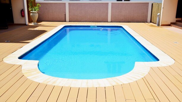 Ein rechteckiger Pool mit einer ihn umgebenden Holzterrasse.
