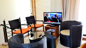 A living room with a television, two chairs, a small table, and a wicker chair.