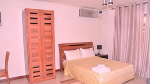 A bedroom with a bed, wooden wardrobe, and a nightstand.