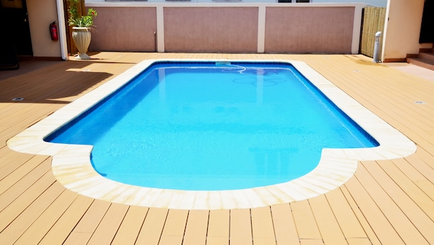A rectangular swimming pool with a wooden deck surrounding it.