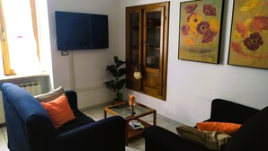 A living room with a TV, two sofas, a coffee table, a plant, and two paintings on the wall. - Fabulous Apartment in the Historic Center, Bright and With Easy Parking (Spoleto)