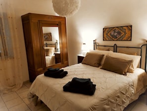 A bedroom with a bed, a nightstand, a mirror, a lamp, and a painting on the wall. - Fabulous Apartment in the Historic Center, Bright and With Easy Parking (Spoleto)