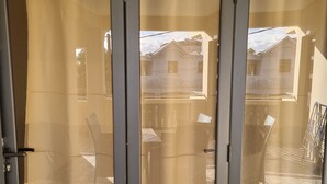 A door with a sign reading "Oiseau du paradis" and a view of a residential area with houses and a parked car. - Residence La Colombe Vacation Rentals Ground Floor (Trou aux Biches)
