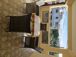 A balcony with a table and chairs, a tiled floor, and a view of buildings and trees. - Residence La Colombe Vacation Rentals Ground Floor (Trou aux Biches)