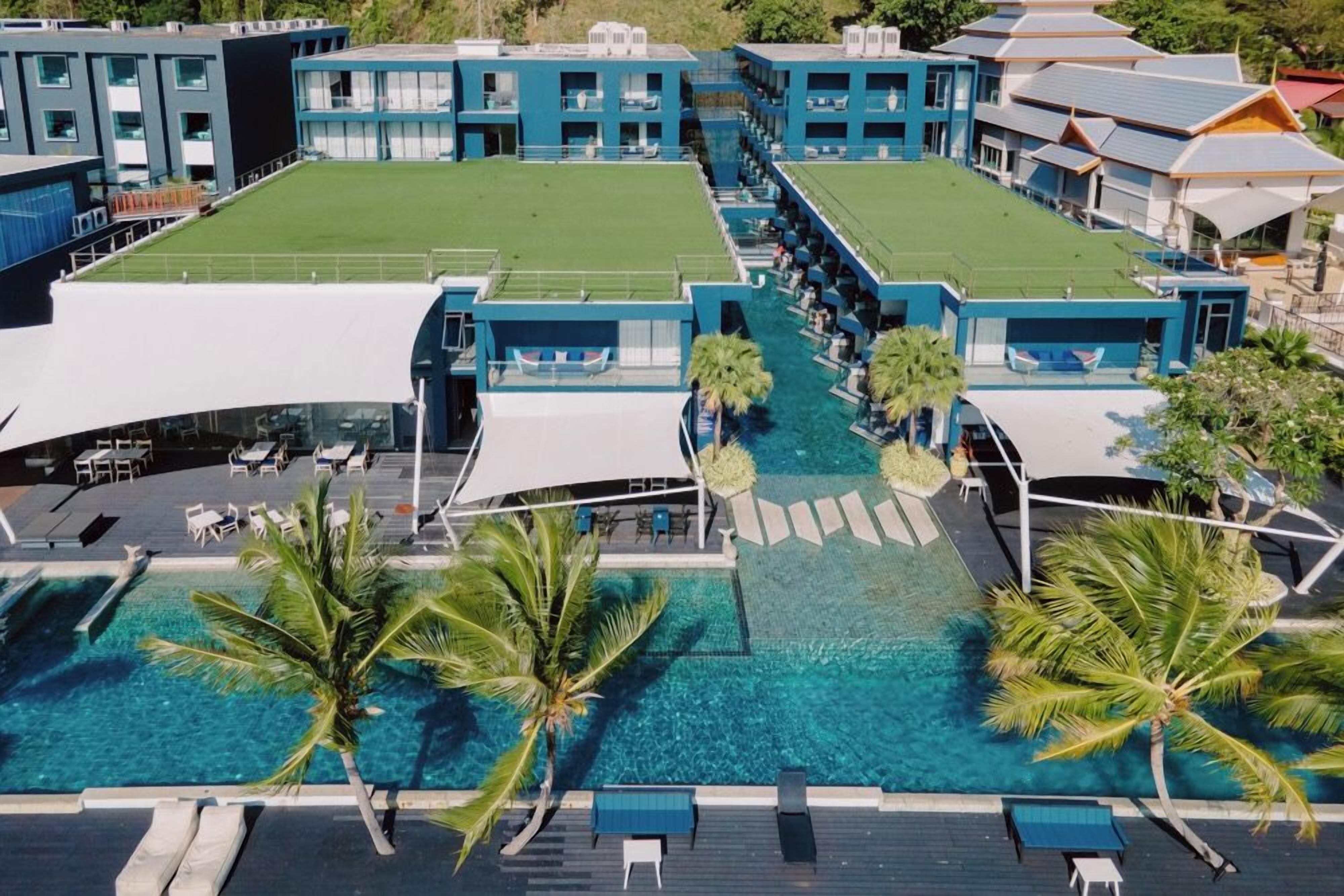 A hotel with multiple buildings, a swimming pool, and palm trees.
