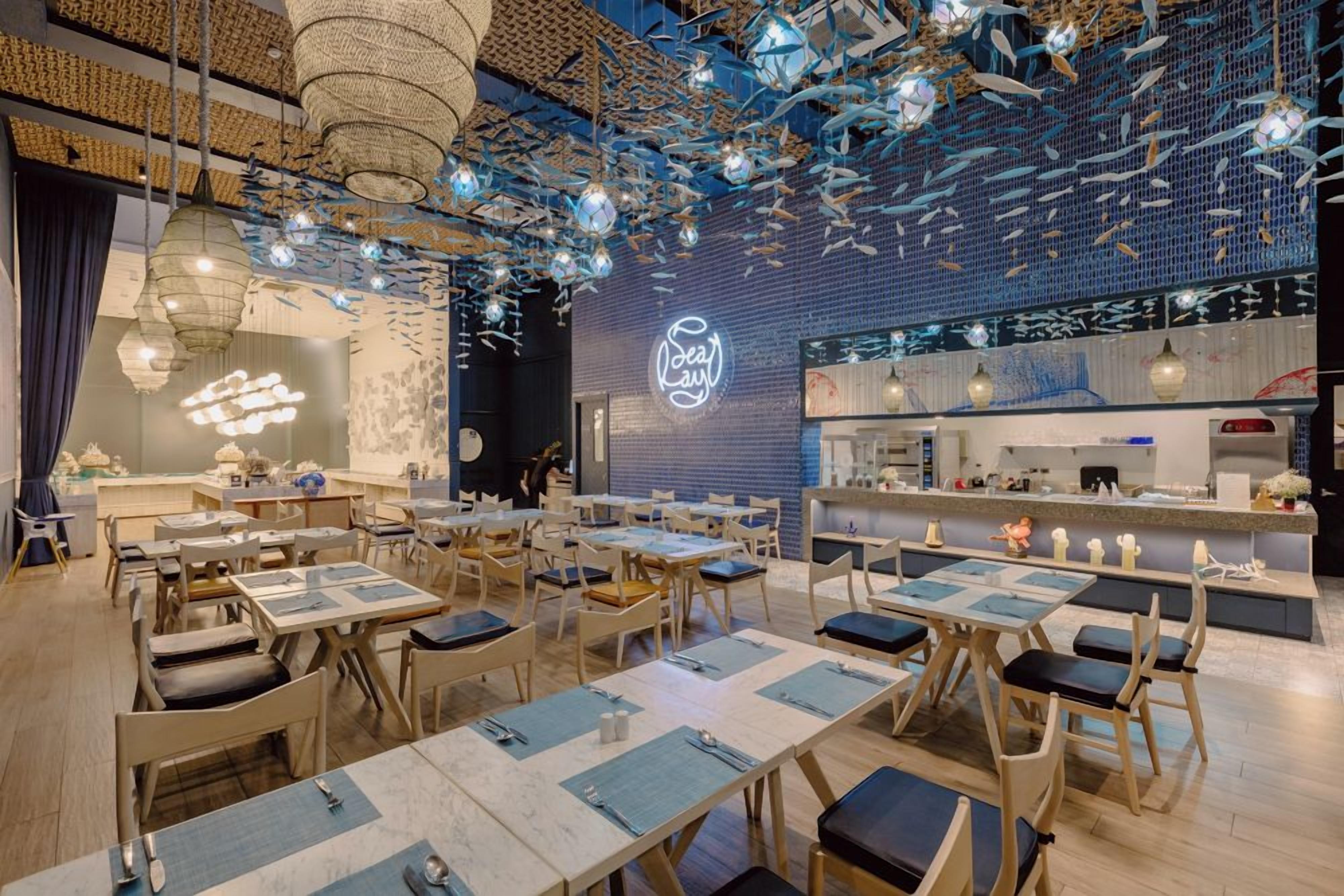 A restaurant interior with tables and chairs, a counter, and hanging decorative elements.