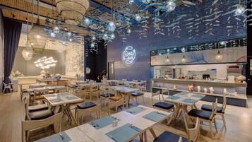 A restaurant interior with tables and chairs, a counter, and hanging decorative elements.