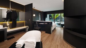 A modern hotel room with a large bed, a desk, a mirror, and a view of palm trees. - Hotel Tide Phuket (Ratsada)