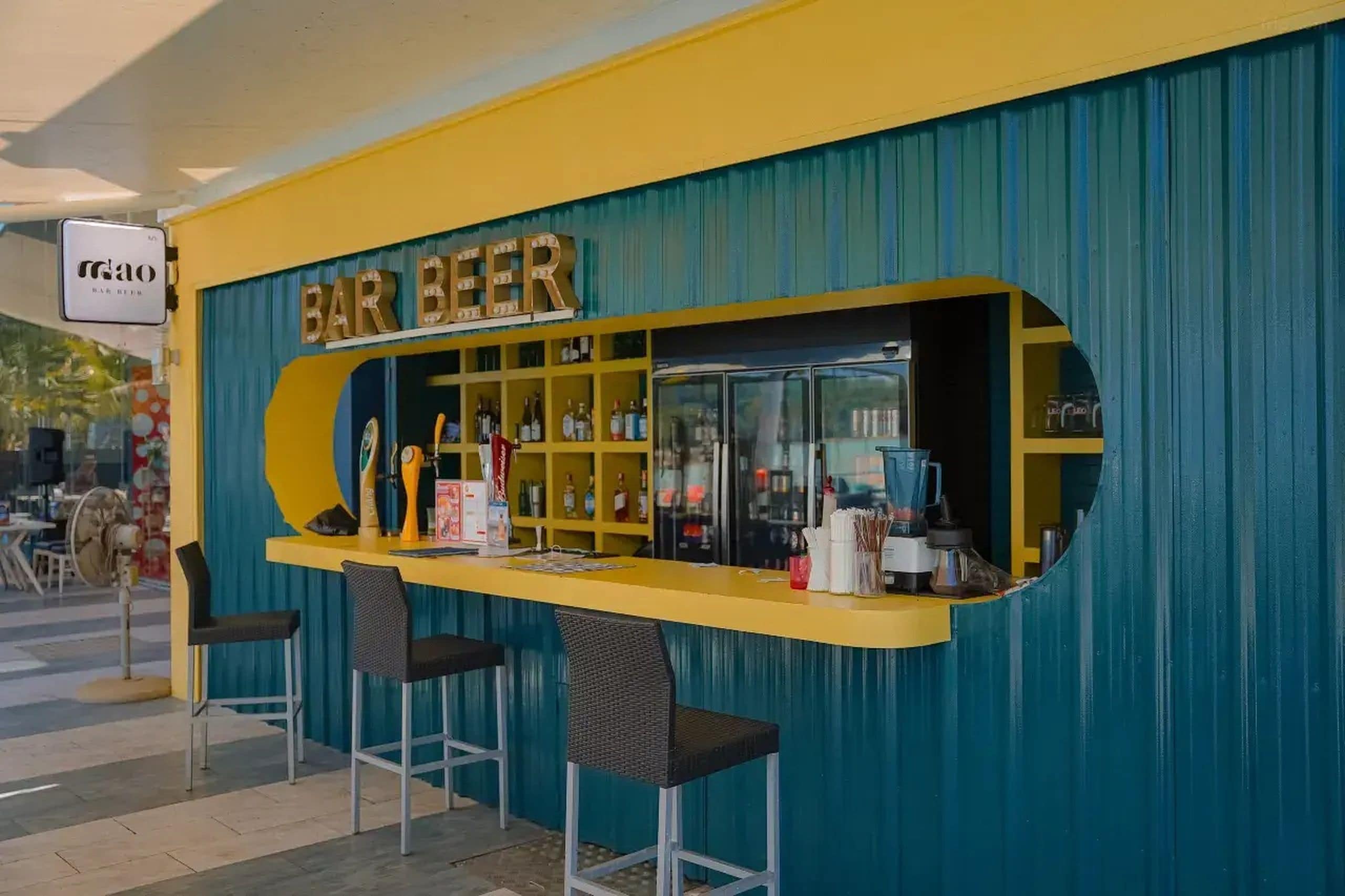 Un bar con mostrador amarillo y pared azul, con un letrero que dice 'BAR BEER'.