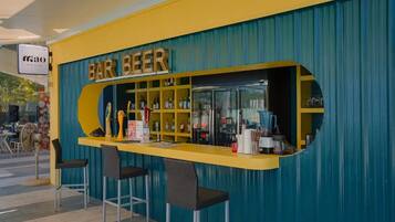 Un bar con mostrador amarillo y pared azul, con un letrero que dice 'BAR BEER'.