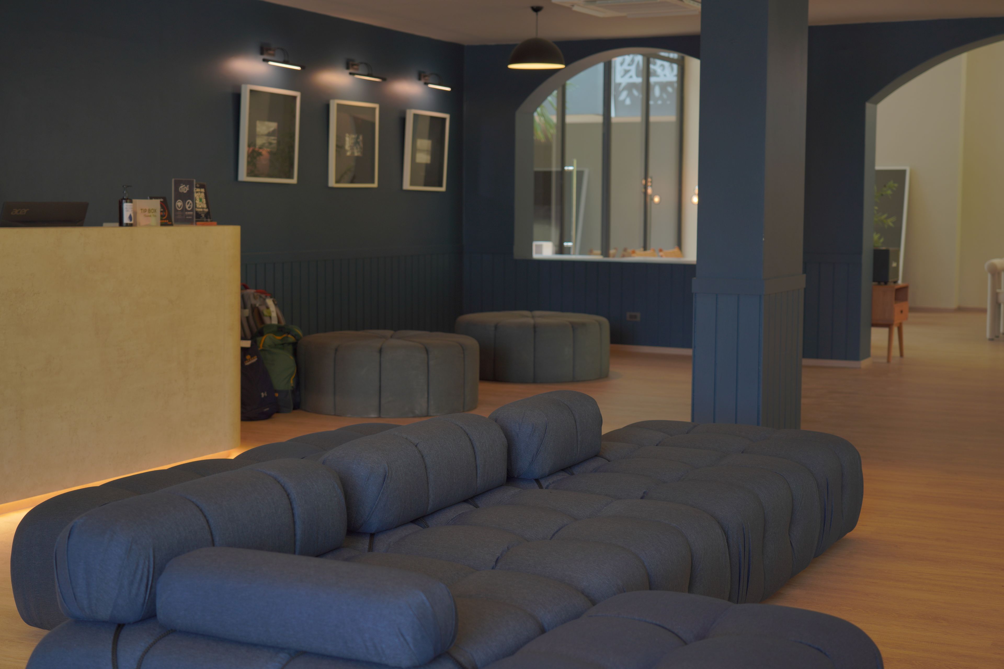 A modern living room with a sectional sofa, a wooden reception desk, and framed artwork on the wall.