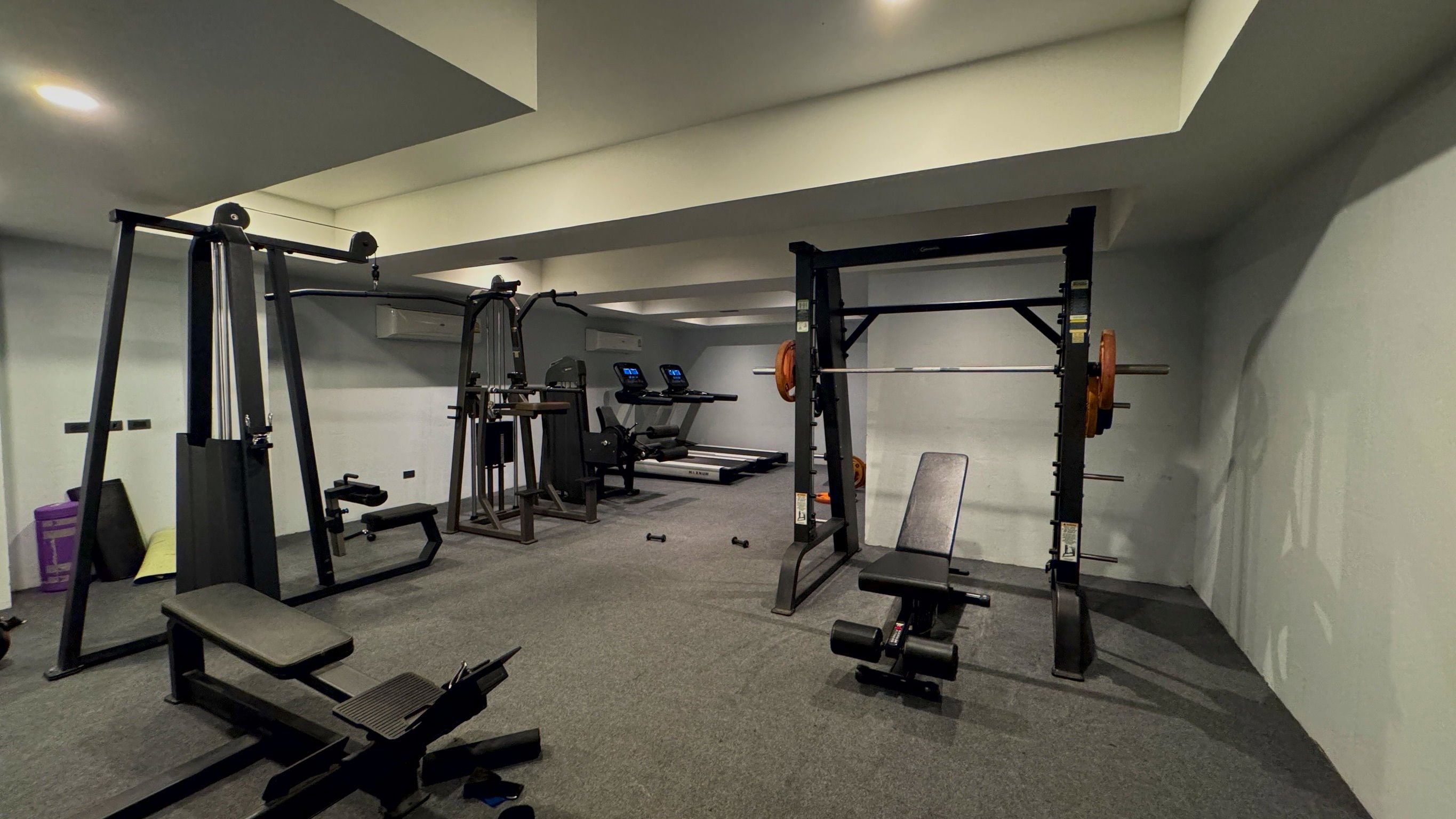 Een sportschool met gewichthefapparatuur, loopbanden en banken.