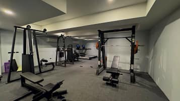 Een sportschool met gewichthefapparatuur, loopbanden en banken.