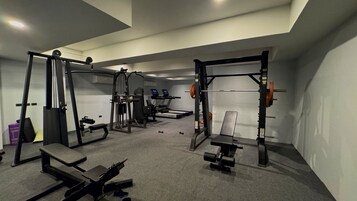 Een sportschool met gewichthefapparatuur, loopbanden en banken.