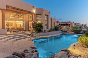 A pool area with a stone deck, lounge chairs, and a building with large windows and a door. - Golf Colony w/Golf, Mt & City Views: Salt H2O Pvt POOL, Spa, Kiva Fireplace, TVs All BRs (Mesa)