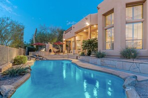 A swimming pool with a stone border, a patio area with outdoor furniture, and a building with large windows. - Golf Colony w/Golf, Mt & City Views: Salt H2O Pvt POOL, Spa, Kiva Fireplace, TVs All BRs (Mesa)