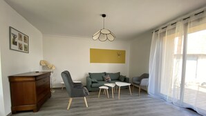 Un soggiorno moderno con un divano, due poltrone, un tavolino da caffè e un mobiletto in legno.