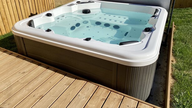 Una vasca idromassaggio con un pontile in legno e una recinzione di legno sullo sfondo.