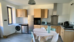 Una cucina compatta con mobili in legno, una lavatrice, un forno a microonde e un'area pranzo con tovaglia a righe.