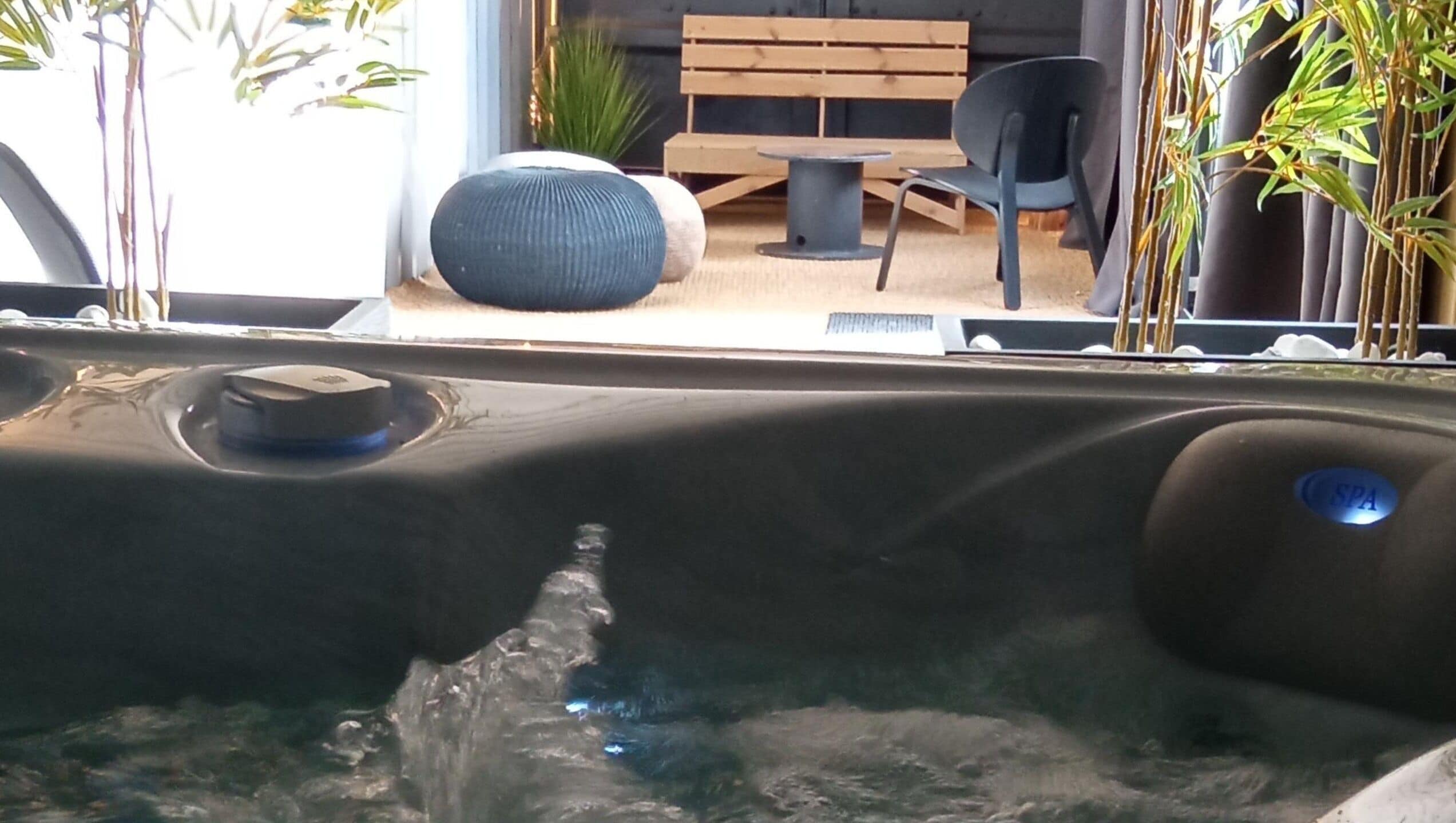 A spa area with a hot tub, wooden furniture, and potted plants.
