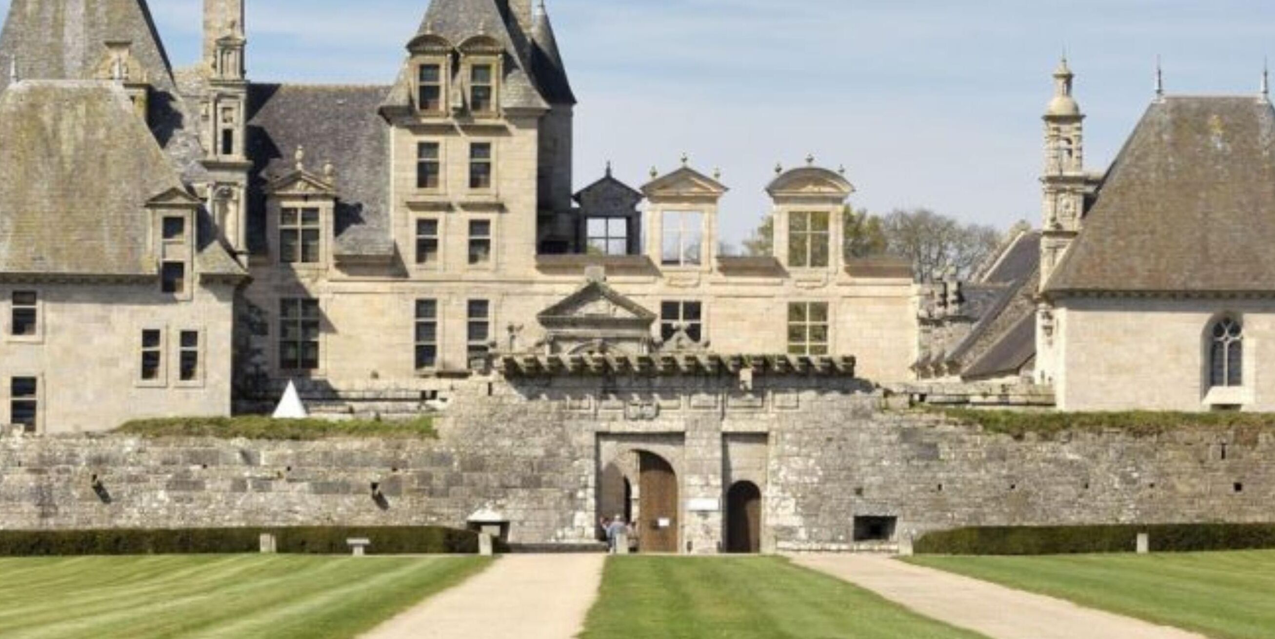 Un bâtiment historique doté d’une entrée centrale, de murs en pierre et d’une façade symétrique.