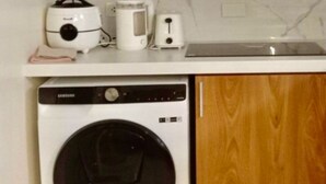 A compact kitchen with a microwave, toaster, and coffee maker on the countertop, and a washing machine below. - FULLY FURNISHED 2 BEDROOM CONDO UNIT (Pasig)