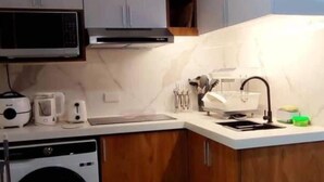 A compact kitchen with a washing machine, microwave, and a sink. - FULLY FURNISHED 2 BEDROOM CONDO UNIT (Pasig)