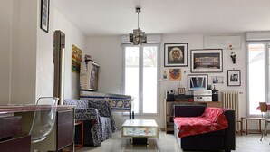 A living room with a sofa, a coffee table, a TV, and a bookshelf. - Charming town house very close to Paris. (Pantin)