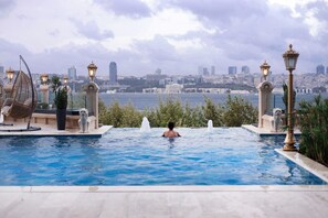 A pool with a cityscape view, surrounded by decorative elements and a statue. - A11 Hotel Bosphorus (Istanbul)