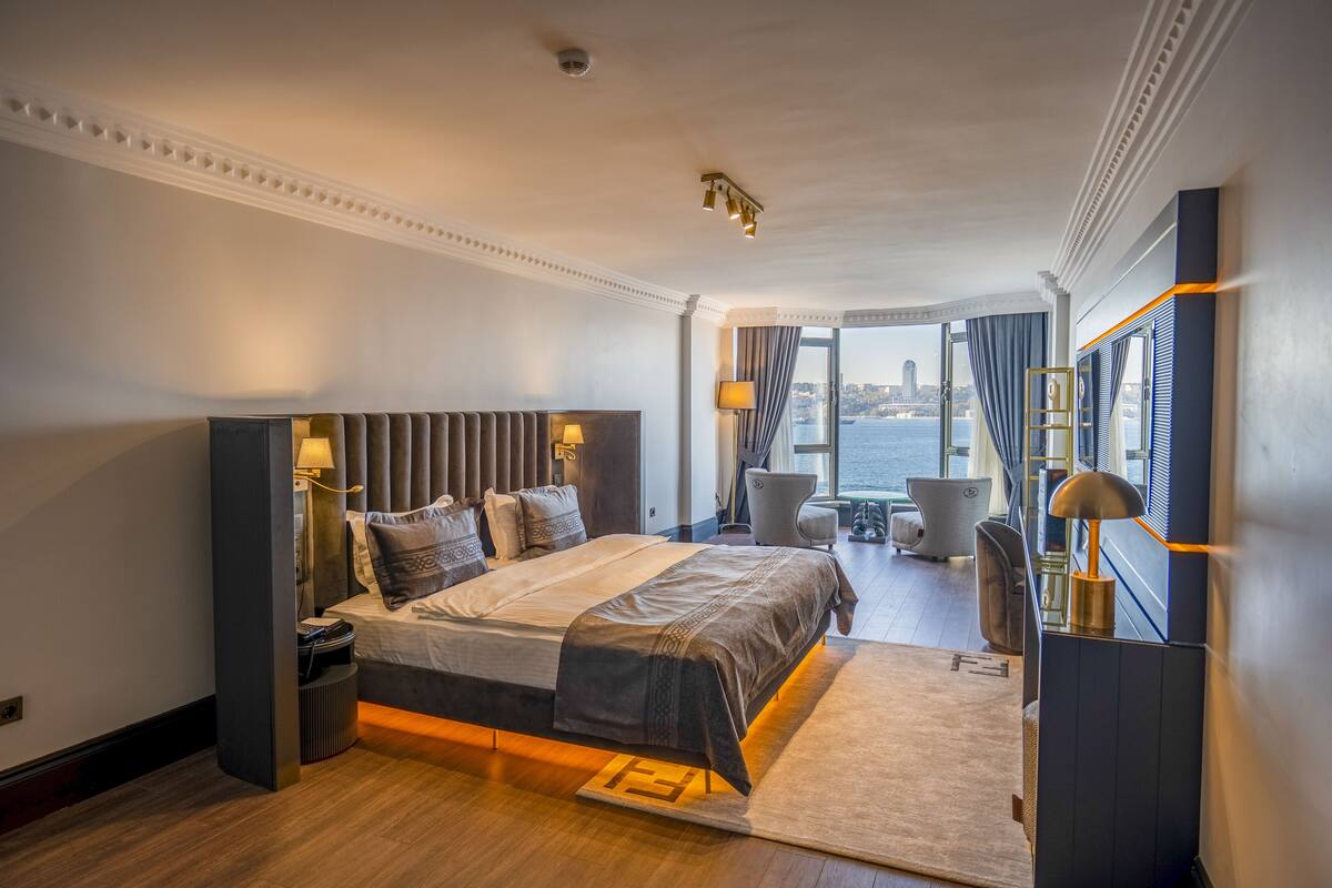 A modern hotel room with a large bed, a view of the city, and a balcony.