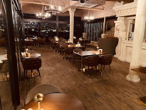 An indoor dining area with wooden flooring, multiple tables and chairs, and a view of the cityscape through large windows. - A11 Hotel Bosphorus (Istanbul)