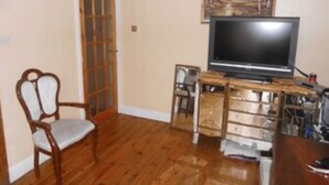 A room with a wooden floor, a television on a stand, a chair, and a door with glass panels. - Big Lux Double Family room all Modern house. (Wembley)