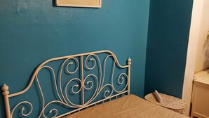A bed with a metal headboard against a teal wall, a framed picture above, and a bedside table with a lamp. - Big Lux Double Family room all Modern house. (Wembley)