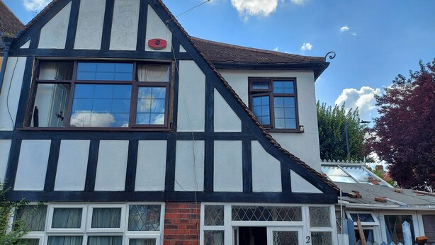 A traditional half-timbered house with two visible windows, a brick chimney, and a number '2' sign on the door. - Big Lux Double Family room all Modern house. (Wembley)