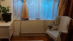 A bedroom with a window, a radiator, a chair, and a bedside table with a plant. - Big Lux Double Family room all Modern house. (Wembley)