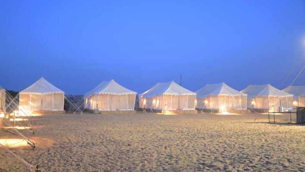 A row of white tents with a flat roof, arranged in a line on a sandy beach at dusk. - Riddhi Siddhi Resort (Jaisalmer)