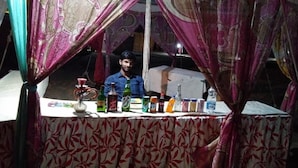 A man sitting behind a table with various bottles and containers, possibly a vendor or service provider. - Riddhi Siddhi Resort (Jaisalmer)