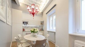Eine moderne Küche mit weißen Schränken, einer zentralen Kochinsel mit Sitzgelegenheiten und einem roten Kronleuchter.