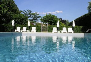 A clear swimming pool with white lounge chairs and umbrellas, surrounded by greenery. - Charming house with a garden. Swimming pool. 8 minutes from Saint-Rémy (Graveson)
