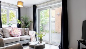 En stue med sofa, rundt sofabord, en potteplante og et fjernsyn.