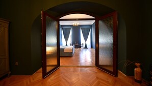A room with a wooden herringbone floor, a bed, a small table, and a chair. - Lovely 2 bedroom apartment in historic city center (Sibiu)