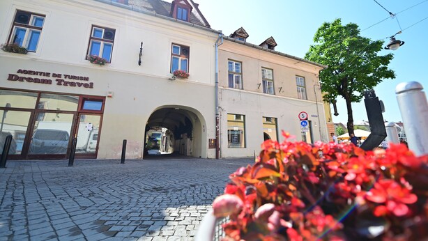 A building with a sign reading "AGENTIE DE TURISME Dream Travel" and an archway entrance. - Lovely 2 bedroom apartment in historic city center (Sibiu)