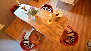 A wooden dining table with candles, a vase with flowers, and a bottle of champagne. There are four wooden chairs around the table. - Lovely 2 bedroom apartment in historic city center (Sibiu)