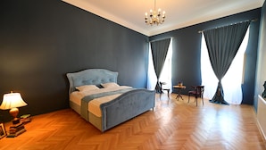 A bedroom with a bed, a chandelier, a small table, and two chairs. - Lovely 2 bedroom apartment in historic city center (Sibiu)